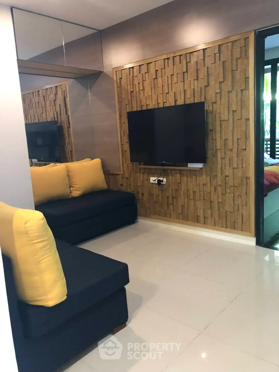 Modern living room with stylish wood paneling and mounted TV, featuring cozy seating and vibrant cushions.