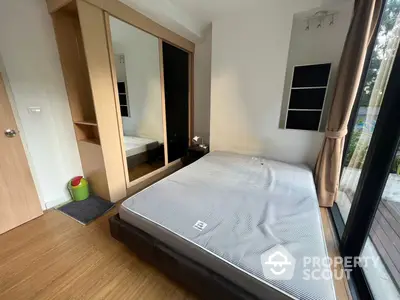 Cozy bedroom with large mirror wardrobe doors reflecting natural light, complemented by wooden flooring and a full-sized bed.