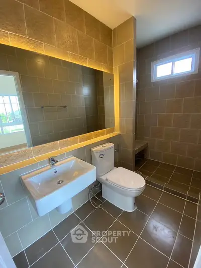 Modern bathroom with sleek fixtures and large mirror in a stylish real estate property.