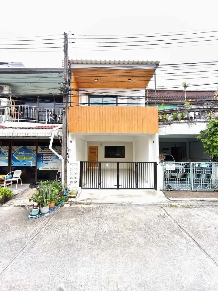 Modern townhouse with wooden facade and gated entrance in urban setting