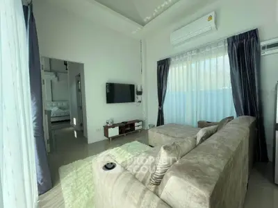 Modern living room with plush sofa, wall-mounted TV, and large windows for natural light.