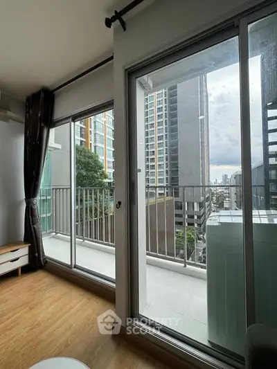 Modern apartment balcony with city view and large sliding glass doors.