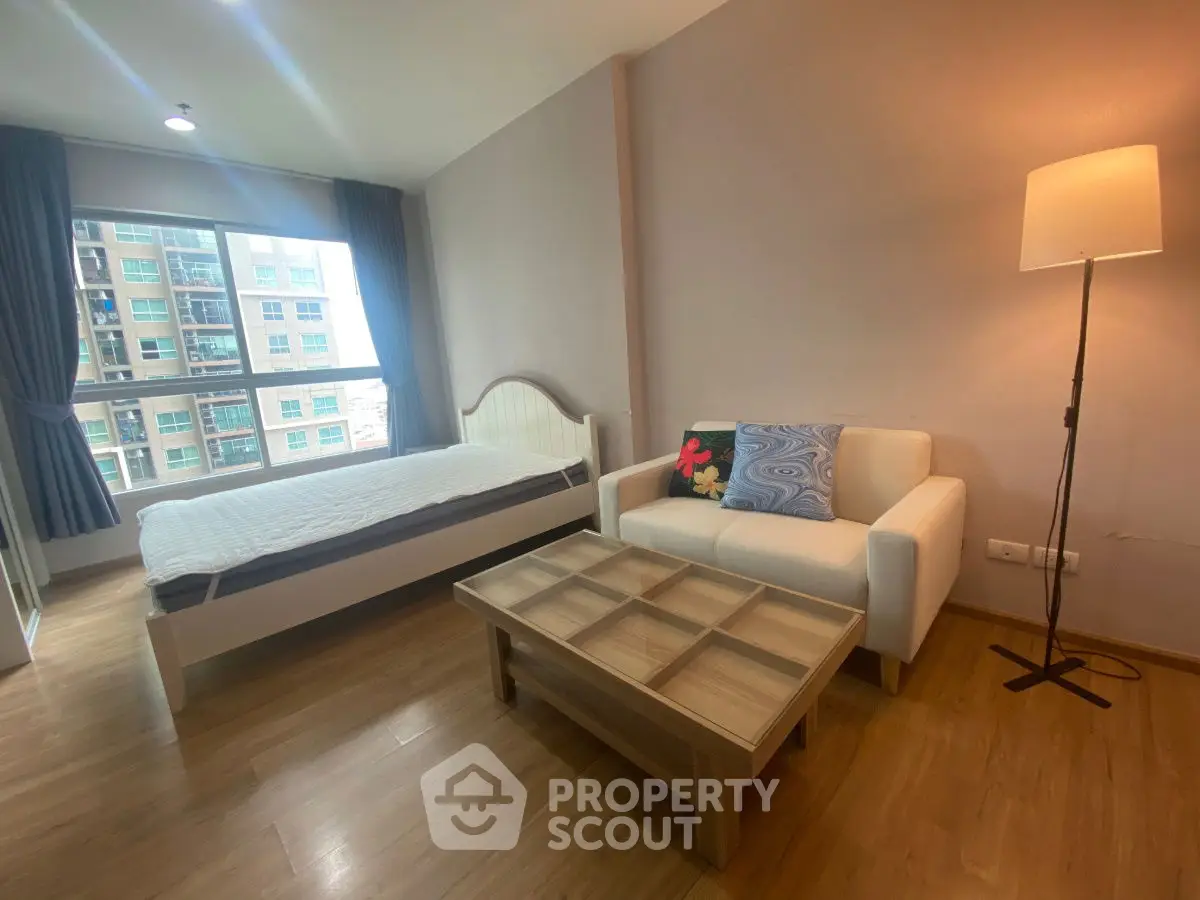 Cozy bedroom with natural light, modern furnishings, and wooden flooring in a stylish apartment.