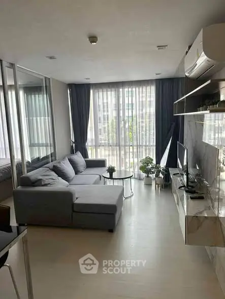 Modern living room with large windows and stylish gray sofa in a contemporary apartment.