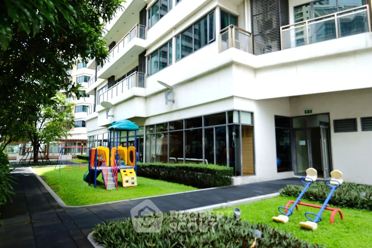Modern apartment building with outdoor playground and lush greenery