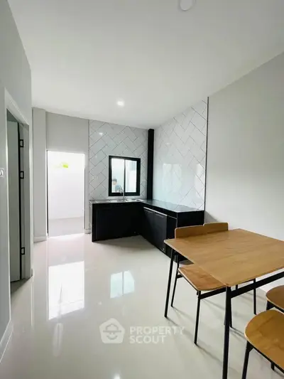Modern kitchen with sleek black cabinets and dining area in bright minimalist design.