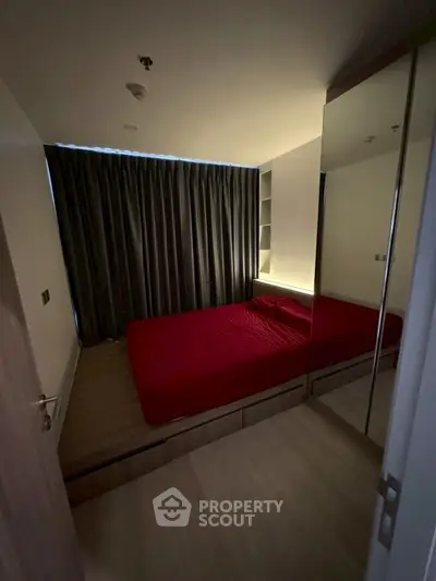 Cozy bedroom with red bedding and mirrored wardrobe, perfect for modern living.
