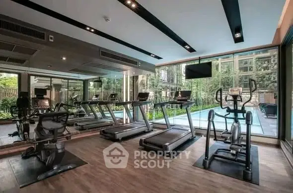 Modern gym with state-of-the-art equipment and large windows overlooking a lush garden.