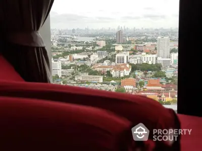 Stunning cityscape view from a high-rise apartment window with red curtains.