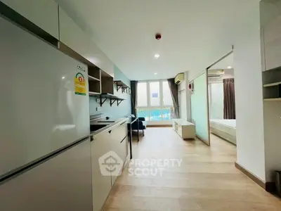 Modern open-plan apartment with sleek kitchen and cozy living area, featuring large windows and natural light.