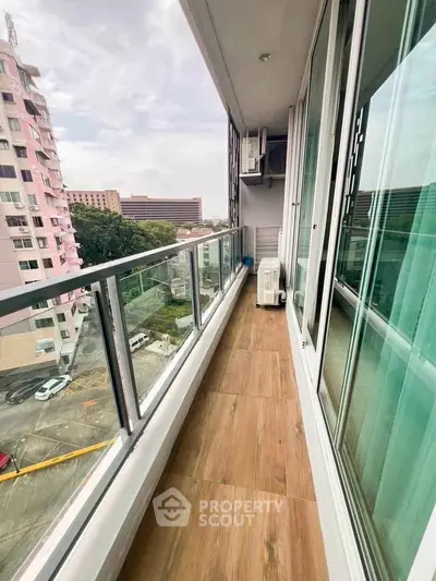 Spacious balcony with glass railing and city view, perfect for relaxation and enjoying the outdoors.