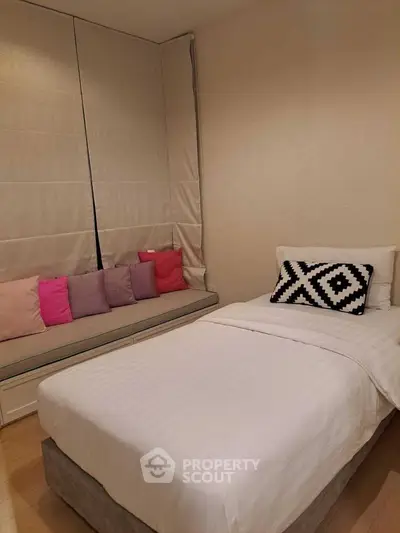 Cozy bedroom with single bed and colorful cushions, perfect for relaxation.
