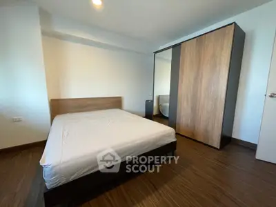 Modern minimalist bedroom with wooden flooring and sleek wardrobe