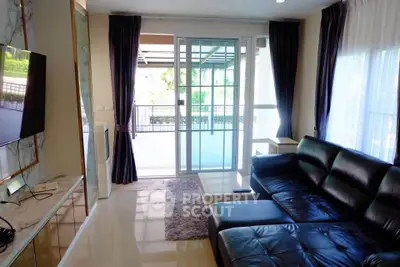 Modern living room with sleek black leather sofa and large glass doors leading to balcony.