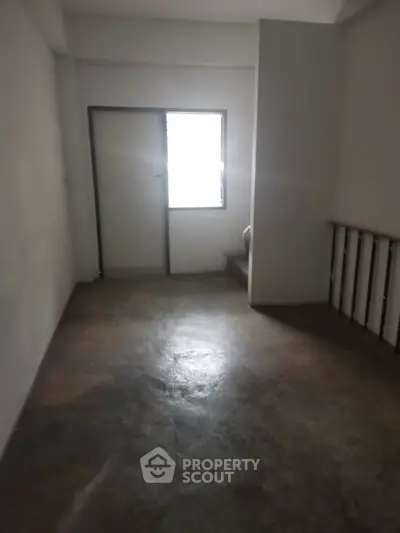 Spacious empty room with concrete floor and window, ideal for customization.