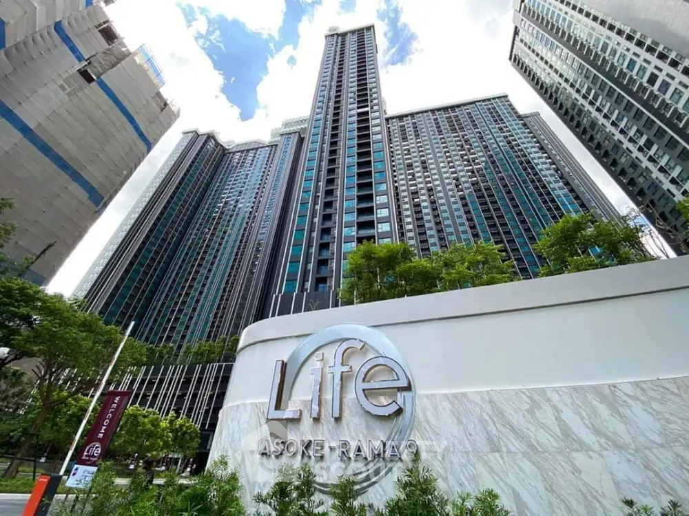 Modern high-rise condominium Life Asoke Rama 9 with lush greenery and urban skyline.