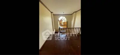 Spacious hallway with wooden flooring and large window, perfect for natural light.