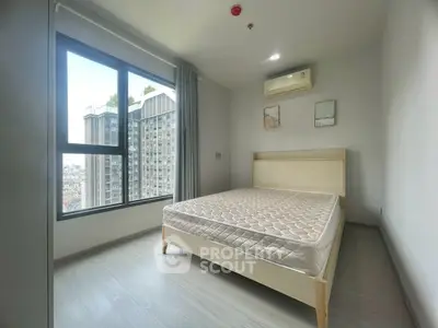 Modern bedroom with large window and city view in high-rise apartment