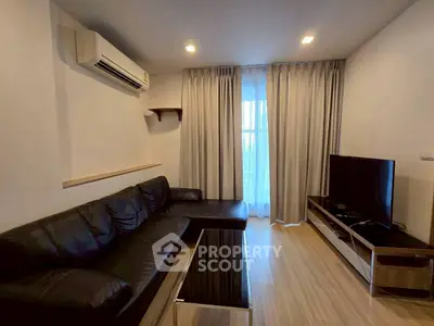 Modern living room with sleek black leather sofa and large TV, featuring elegant wooden flooring and ambient lighting.