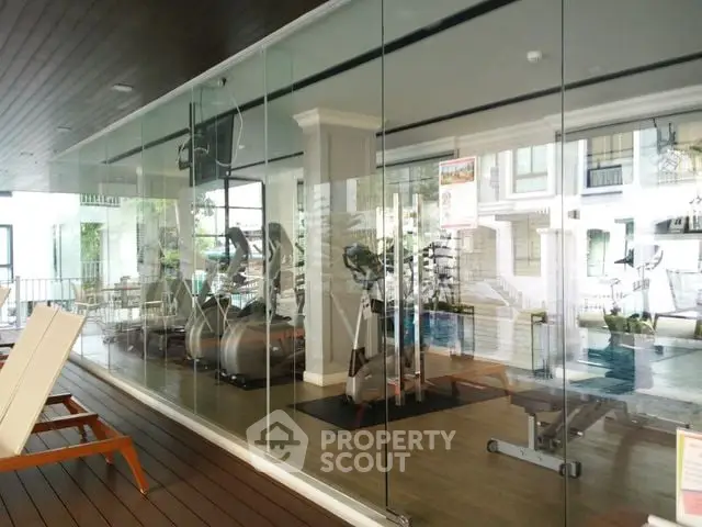 Modern gym with glass walls and state-of-the-art fitness equipment in luxury residential complex.