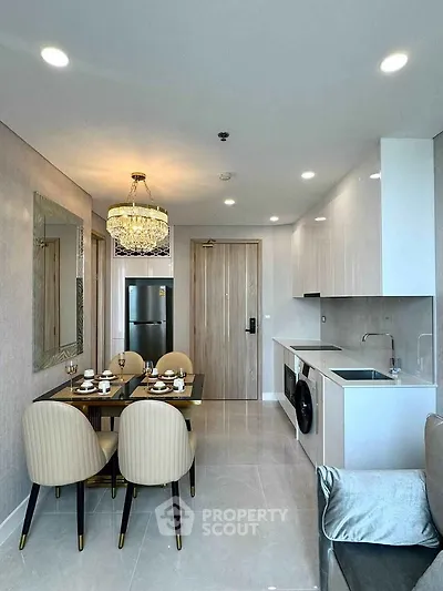Modern open-plan kitchen and dining area with elegant chandelier and sleek appliances.