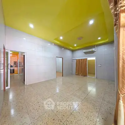 Spacious living room with modern lighting and tiled flooring, perfect for family gatherings.
