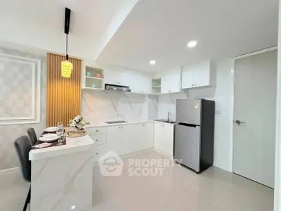 Modern kitchen with sleek white cabinets and stainless steel fridge in a stylish apartment.