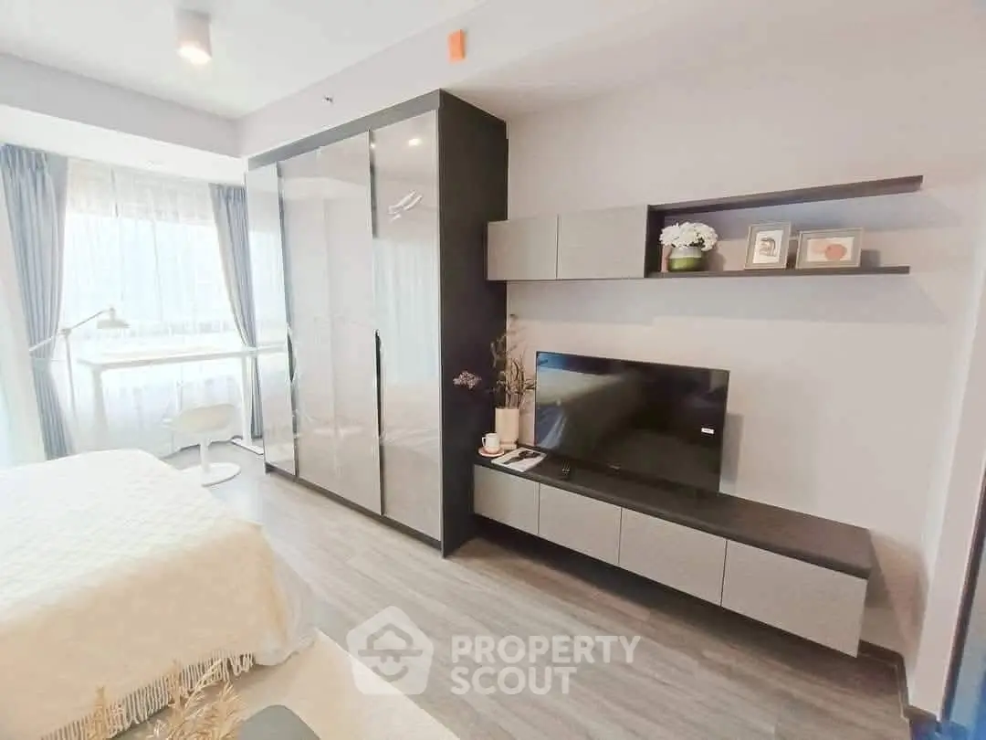 Modern bedroom with sleek wardrobe and TV unit, featuring elegant decor and natural light.