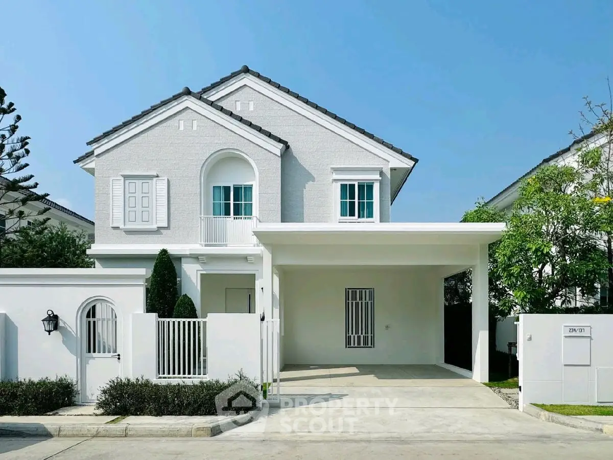 Charming white two-story house with a spacious driveway and lush greenery, perfect for family living.