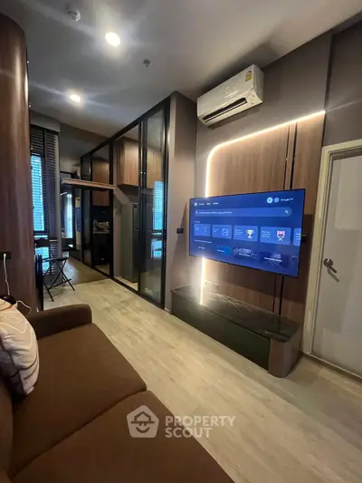 Modern living room with sleek design, featuring a wall-mounted TV and stylish furniture in a cozy apartment.