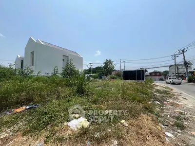 Vacant land plot with potential for development in a suburban area, featuring nearby modern buildings.