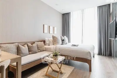 Elegant studio apartment with seamless living and sleeping areas, modern furniture, and abundant natural light.
