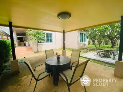 Charming covered patio with outdoor dining set in a serene garden setting