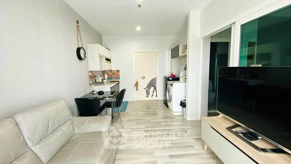 Modern living room with open kitchen, featuring sleek furniture and stylish decor.