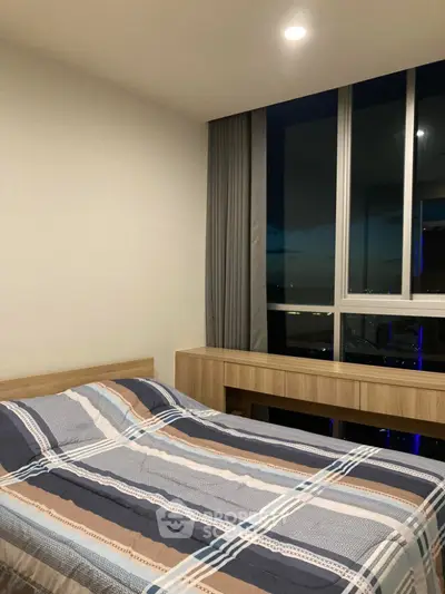 Modern bedroom with large window offering stunning city view, featuring a cozy bed and sleek wooden furniture.