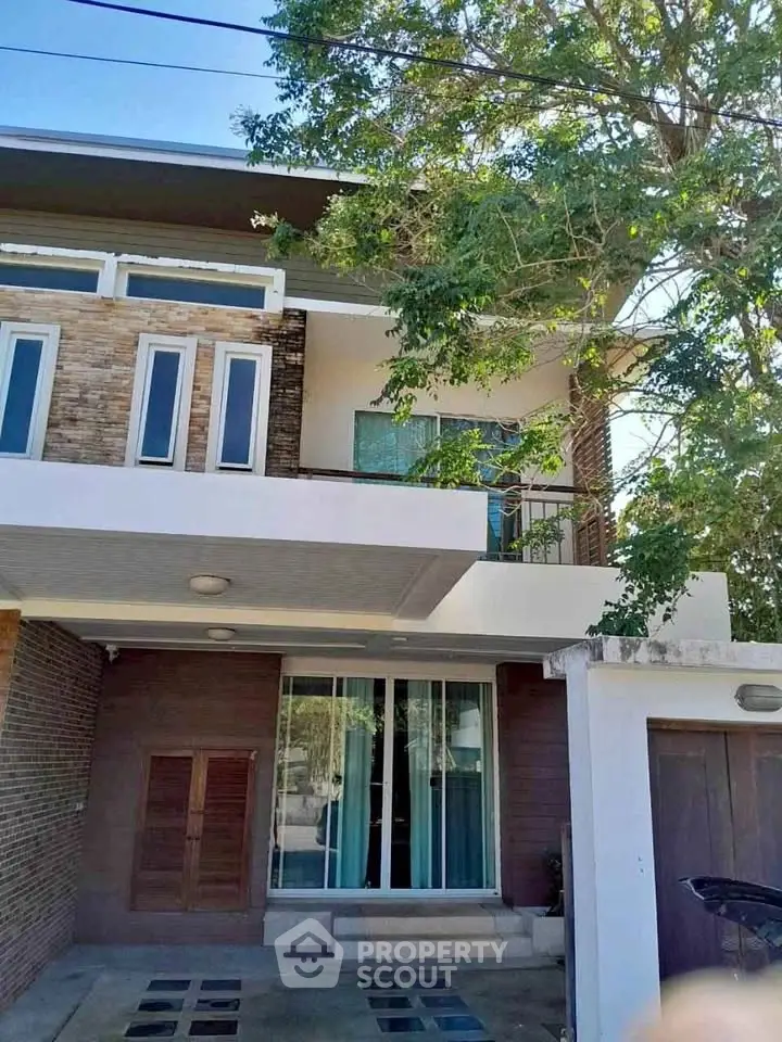 Modern two-story house with large windows and a tree-lined entrance, perfect for family living.