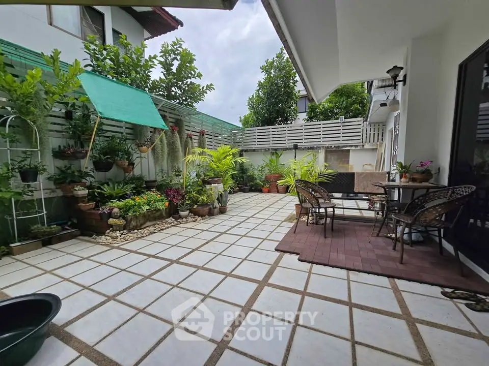 Charming garden patio with lush greenery and cozy seating area, perfect for outdoor relaxation.