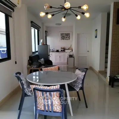 Modern dining area with stylish lighting and open kitchen layout in a cozy apartment.