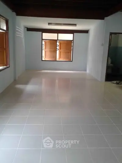 Spacious empty room with tiled flooring and wooden windows, perfect for customization.