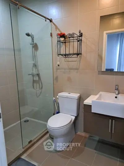 Modern bathroom with glass shower and sleek fixtures in contemporary home.