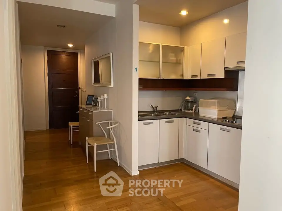 Modern kitchen with sleek cabinetry and wooden flooring in a cozy apartment setting.