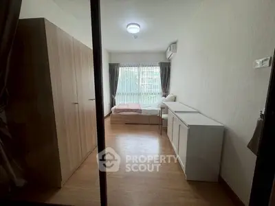Cozy bedroom with wooden flooring, large window, and modern furnishings in a serene apartment setting.