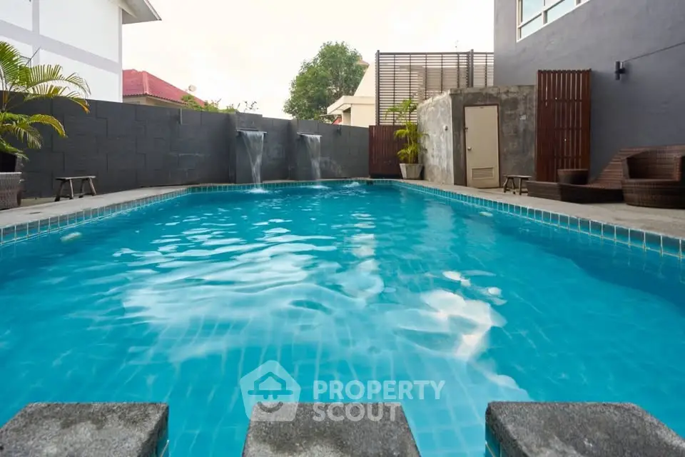 Luxurious outdoor pool area with modern design and cascading water features.