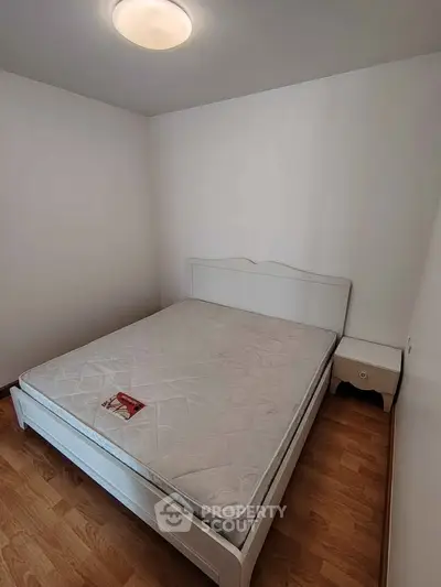 Cozy bedroom with minimalist design featuring a comfortable bed and wooden flooring.