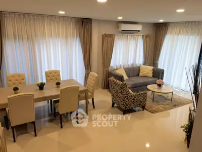 Elegant living room with plush seating and dining area, featuring modern decor and ample natural light.