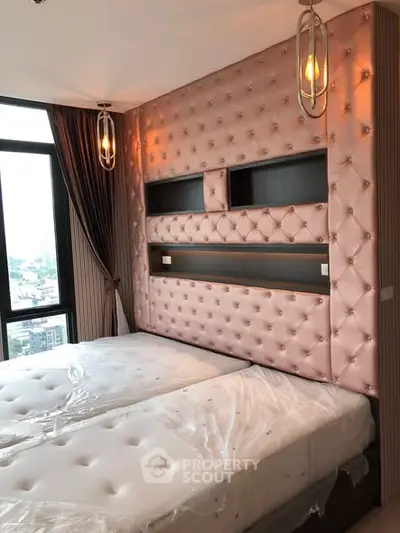 Luxurious bedroom with tufted wall and large windows offering city views.