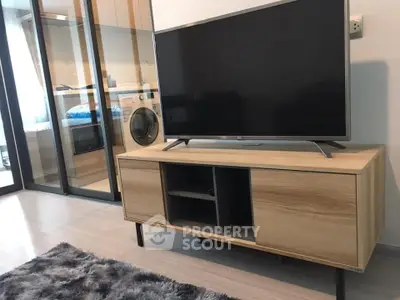 Modern living room with sleek TV stand and washing machine in stylish apartment.