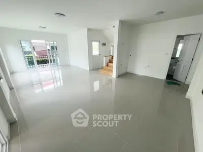 Spacious open-plan living area with glossy tiled floors and natural light.