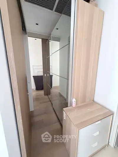 Modern hallway with sleek wooden cabinetry and mirrored closet doors in a stylish apartment.