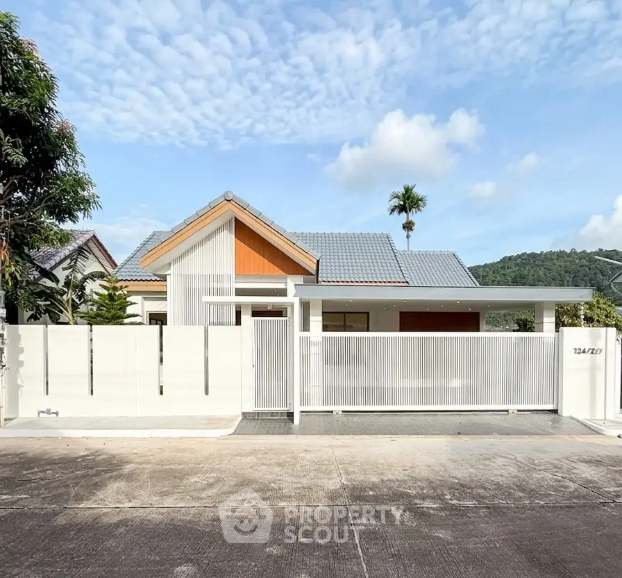 Modern single-story house with sleek white fence and lush surroundings